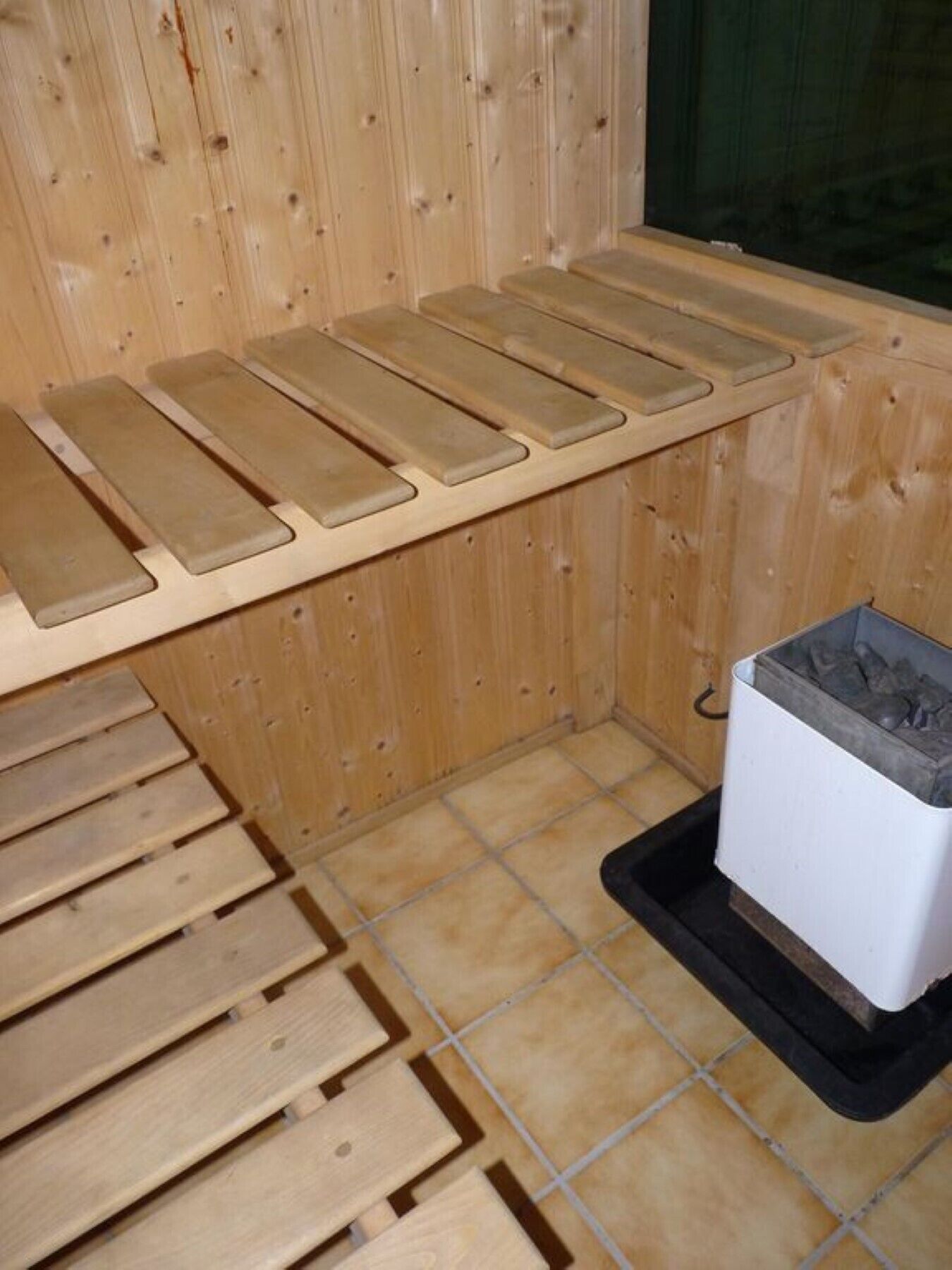 Ein Sauna-Raum mit Holzbänken und einem weißen Heizgerät.