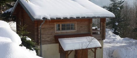 A wooden cabin with a snow-covered roof and a small porch.