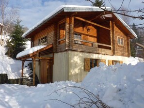 Uma cabana de madeira com varanda, rodeada por neve.