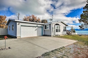Ein zweistöckiges Haus mit Garage, überdachter Veranda und Seeblick.