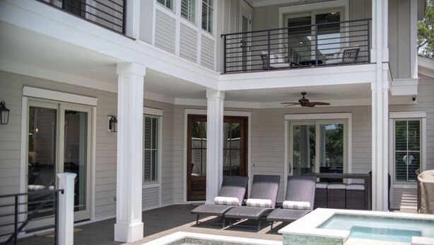 Une maison à deux étages dotée d’un patio couvert, d’une piscine et d’un espace salon extérieur.