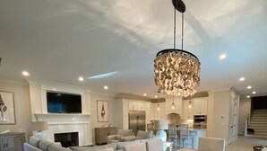 Un vaste salon comprenant une grande table à manger, des sièges confortables, une cheminée et, au fond, un coin cuisine.