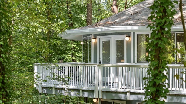 Une terrasse en bois, dotée de rampes de protection, entourée d’une végétation luxuriante.