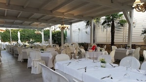 A covered outdoor dining area with white tablecloths and chairs, arranged in rows. - Hotel La Cavalera (Augusta)