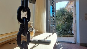 Una cadena colgando del techo, una puerta que da al exterior y un piso de baldosas.