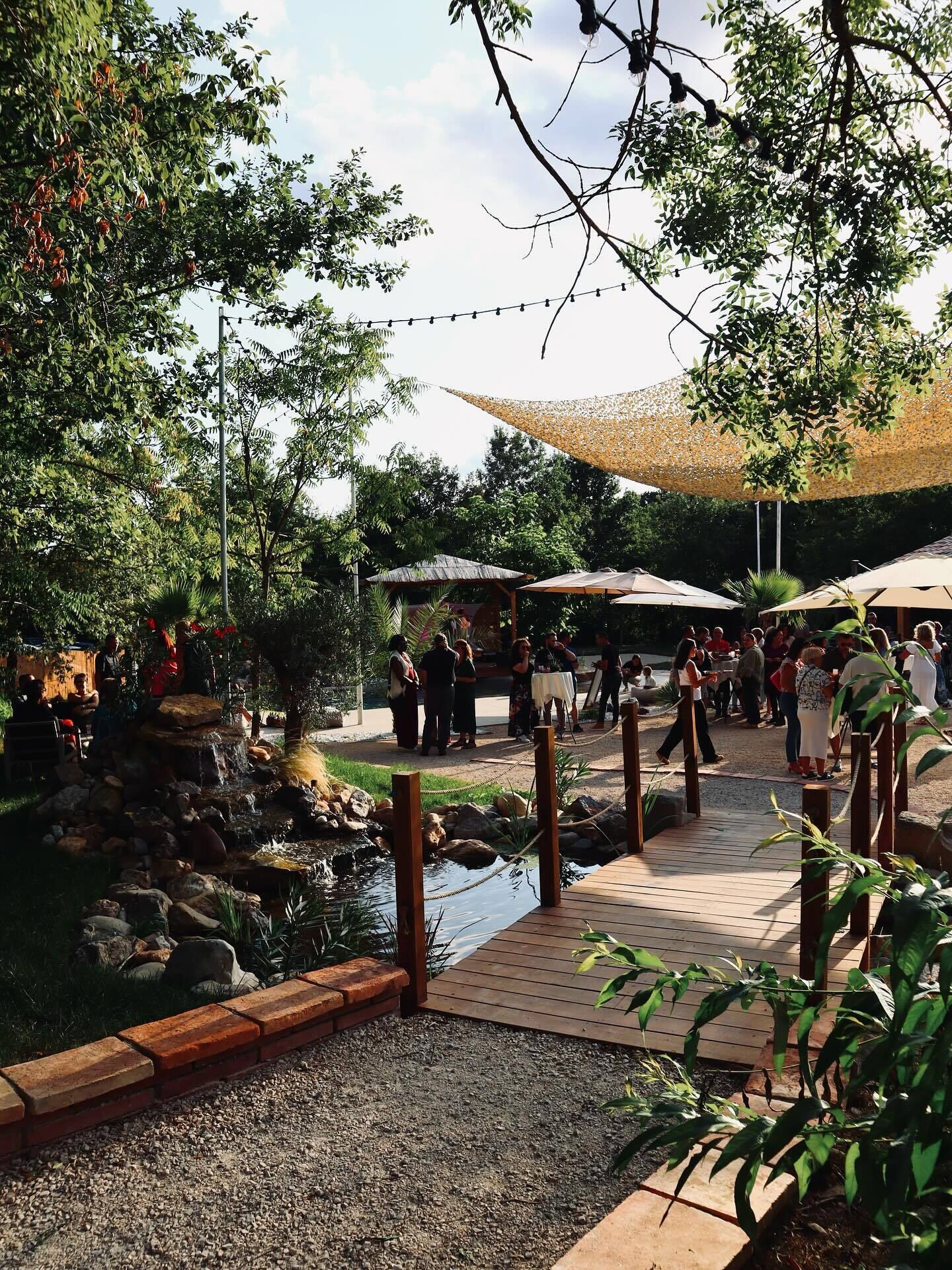 A garden area with a pond, wooden deck, and umbrellas.