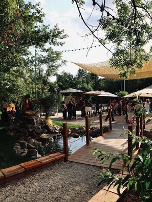 A garden area with a pond, wooden deck, and umbrellas. - L'Alcove Hotel Restaurant (Villemur-sur-Tarn)