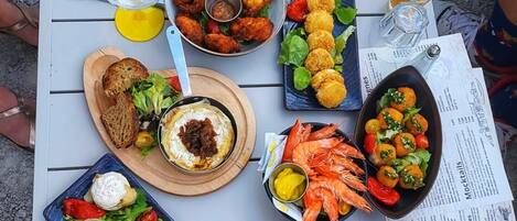 Une table dressée avec divers plats, notamment des fruits de mer, des salades et du pain, ce qui laisse supposer qu’un repas va être servi.