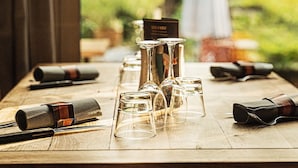 Una mesa de madera con copas de vino, una botella y un menú en un restaurante.