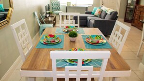 A dining area with a wooden table, white chairs, and colorful plates.