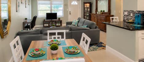 Una sala moderna con comedor, televisor y cocina.
