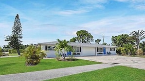 A single-story building with a flat roof, surrounded by a well-maintained lawn and a few trees.