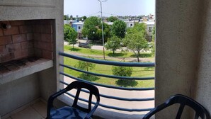 En balkon med en murstensovn, to stole og udsigt over et boligområde.