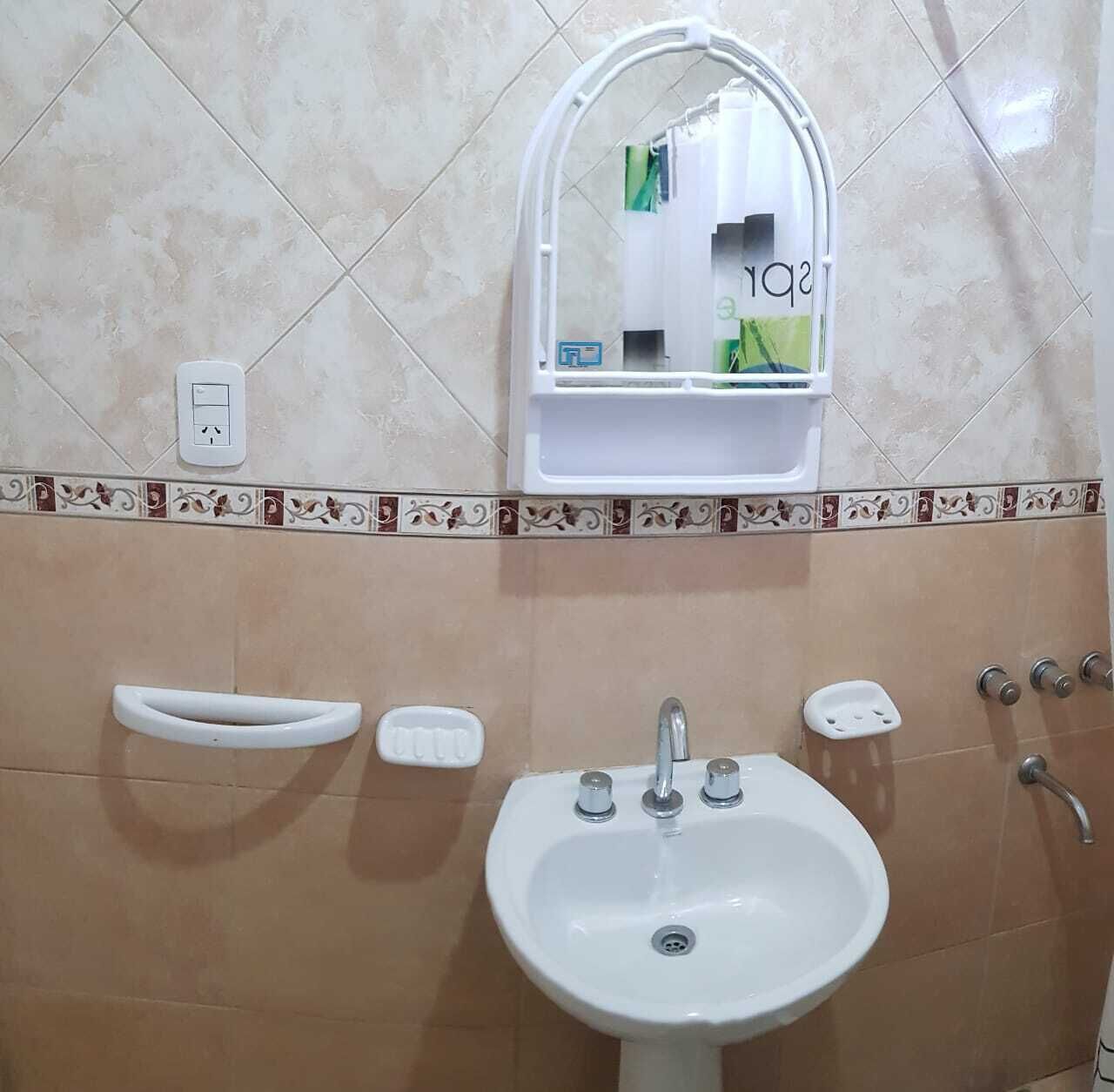 A bathroom with a sink, mirror, soap dish, and towel rack.