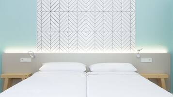 Ein Doppelbett mit weißen Leinen, zwei Nachttische und ein Wandbehang mit geometrischem Muster.