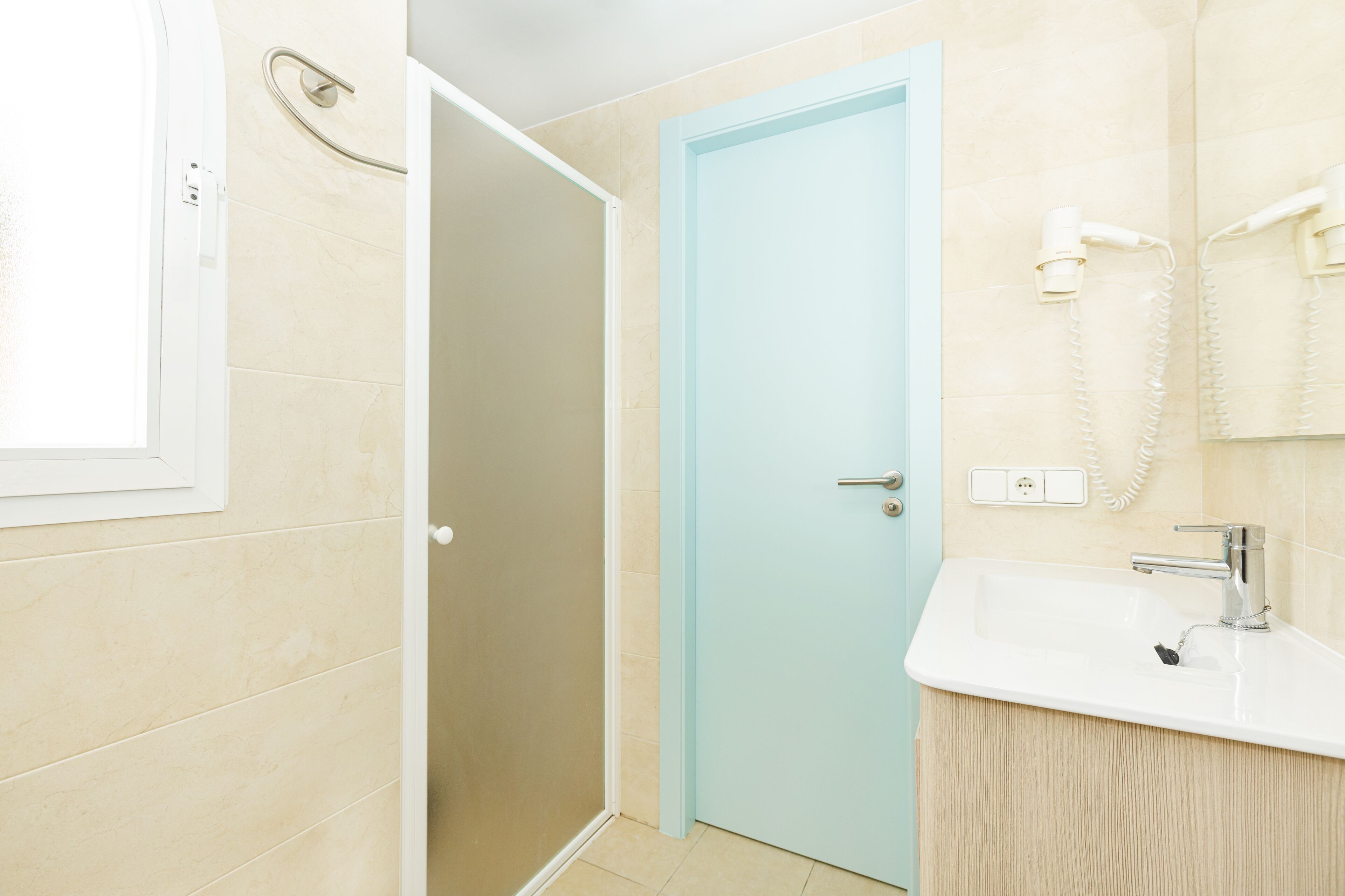 Un baño con ducha, lavamanos y una puerta.