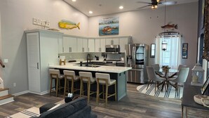 A modern kitchen with a central island, bar stools, and a dining area with a table and chairs. - FLORIDA KEYS PARADISE! DEEP WATER CANAL WITH FAST OCEAN ACCESS. (Summerland Key)