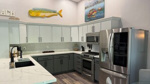A modern kitchen with light grey cabinets, a stainless steel refrigerator, a microwave, and a stove. - FLORIDA KEYS PARADISE! DEEP WATER CANAL WITH FAST OCEAN ACCESS. (Summerland Key)