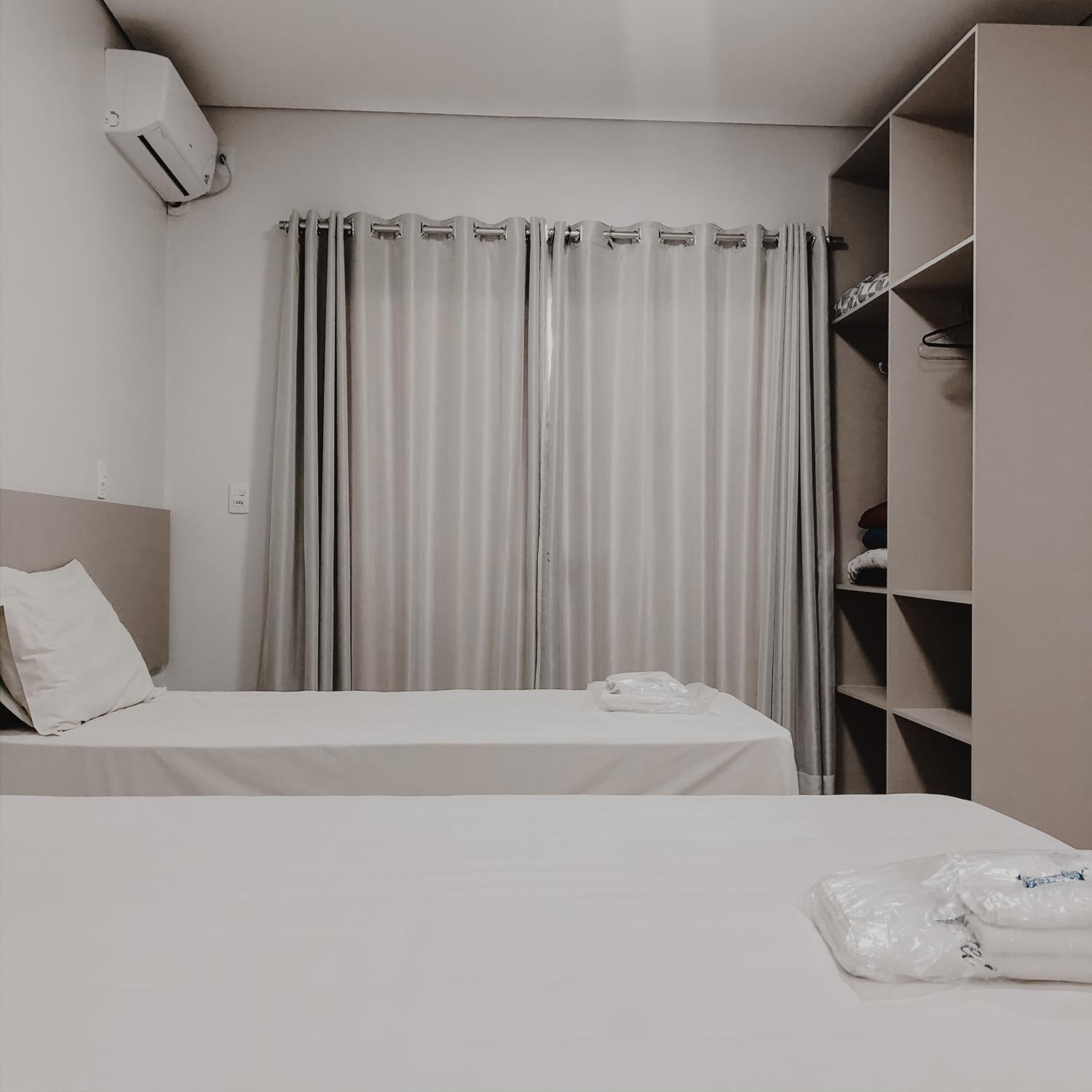 Quarto de hotel com cama, guarda-roupa e cortina.
