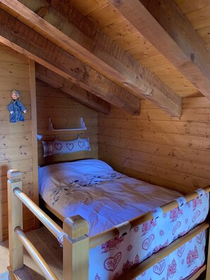 A wooden bunk bed with a white mattress and patterned bedding.