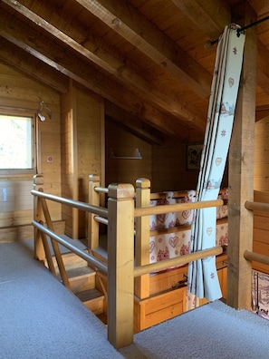A wooden cabin interior with a bunk bed, a window, and a wooden ceiling.