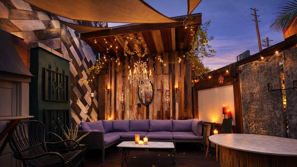 Un espace extérieur aménagé avec un canapé violet, une table ronde et une terrasse en bois.