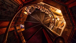 Un escalier en colimaçon au design d’époque, avec des murs en bois et une rampe en métal.