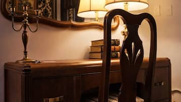 A wooden desk with a lamp, books, and a mirror.