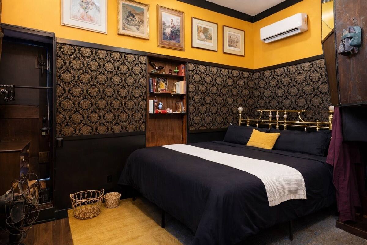 Une chambre à coucher avec un grand lit, une armoire, une bibliothèque et un appareil de climatisation.