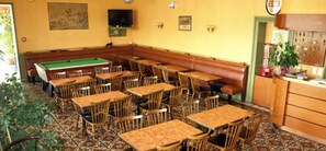 A room with multiple wooden tables and chairs, a pool table, and a television mounted on the wall. - Hotel de la Gare (Lannemezan)