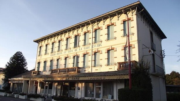 Un hôtel à plusieurs étages, de style architectural classique, doté d’un café au rez-de-chaussée et d’un balcon au deuxième étage.
