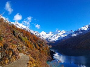 Un paisaje montañoso con cielo despejado, un lago y un camino que lleva hacia las montañas.