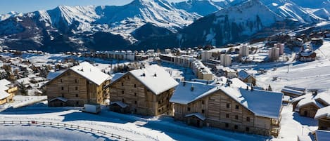 Un pueblo nevado en la montaña con edificios de madera y una pista de esquí.