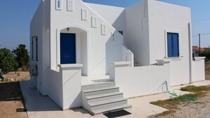 A white building with a blue door and window shutters, featuring a staircase leading to the entrance. - Καλώς ήρθατε στην εξοχική κατοικία στην Αίγινα (Aegina)