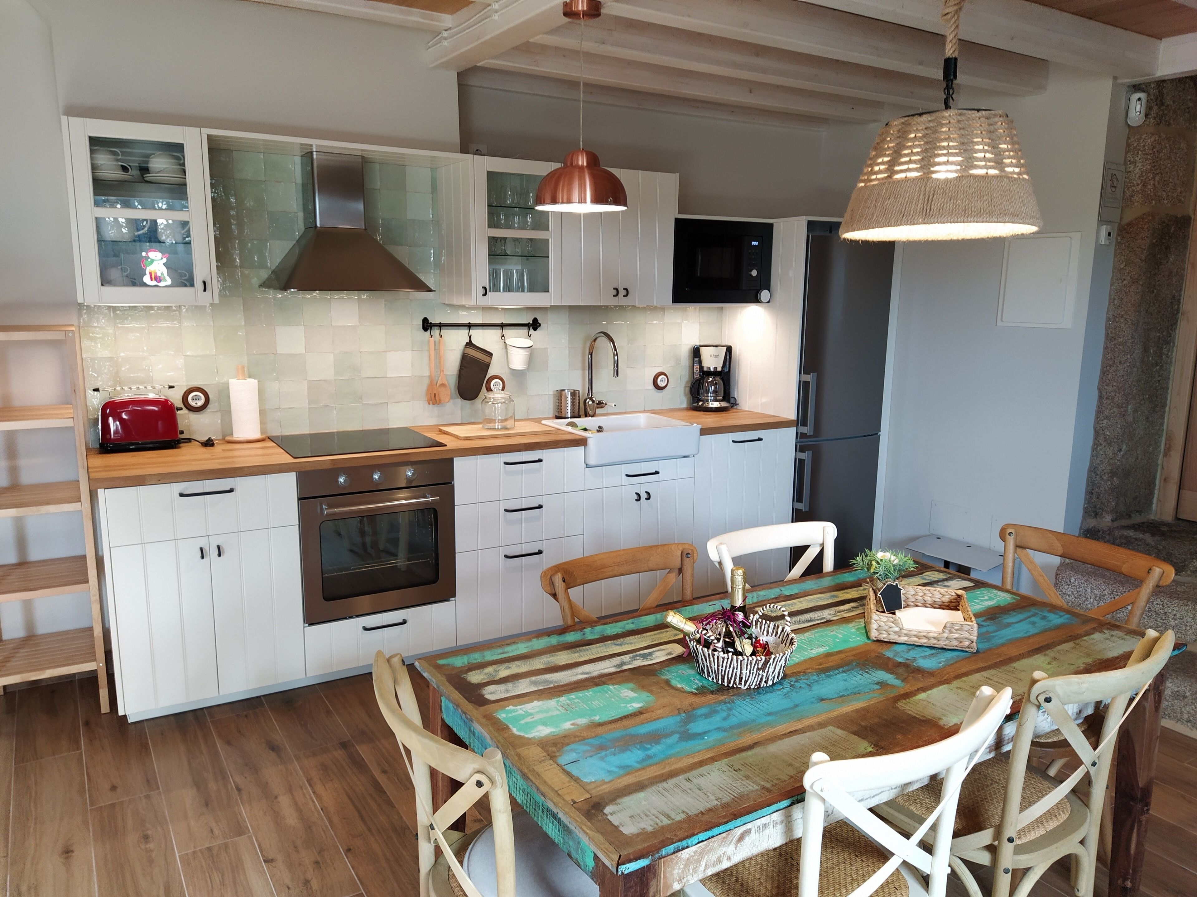 A modern kitchen with white cabinets, a wooden countertop, a red toaster, and a coffee maker.