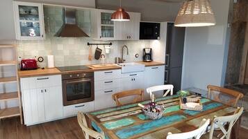 A modern kitchen with white cabinets, a wooden countertop, a red toaster, and a coffee maker.