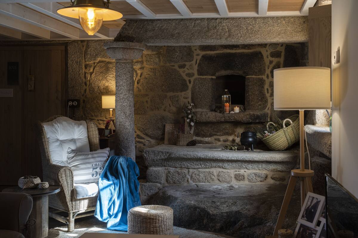 A cozy room with a stone fireplace, wicker furniture, and a lamp.