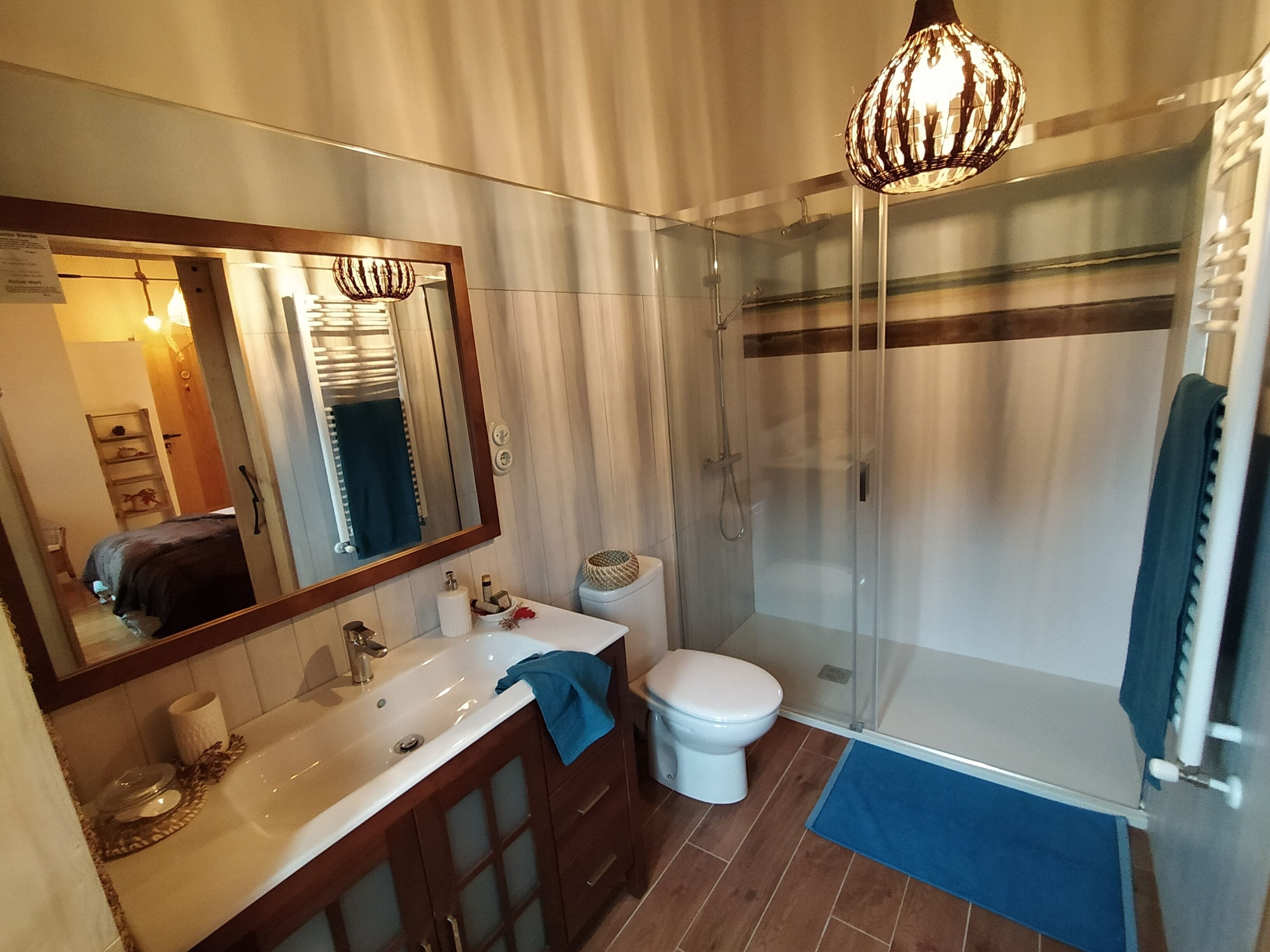 Un baño moderno con cabina de ducha de vidrio, un espejo grande y un lavabo blanco.