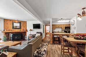 Cozy living and dining area with a central fireplace, comfortable seating, and a modern kitchen.