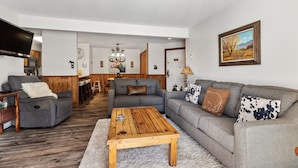 A living room with a gray sofa, a wooden coffee table, and a TV on a stand. - Family-Friendly Comfort at Timber Run – 2-Bedroom Condo Near the Slopes! (Steamboat Springs)