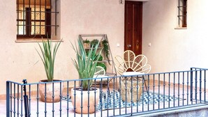 A courtyard with potted plants, a wicker chair, and a metal railing. - ~TIVOLI~ by myhomeintoledo.com (Toledo)