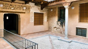 A courtyard with stone walls, tiled flooring, and barred windows. - ~TIVOLI~ by myhomeintoledo.com (Toledo)