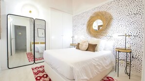A modern bedroom with a large bed, two bedside tables, a mirror, and a decorative wall panel. - ~TIVOLI~ by myhomeintoledo.com (Toledo)