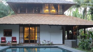 A two-story building with a thatched roof, a swimming pool, and a covered outdoor seating area. - The Wantilan in Tejakula (Tejakula)