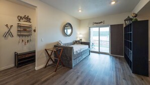 Una habitación amplia con una cama grande, un espacio de descanso, un espejo y un ventanal corredero que da a un área exterior.
