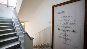 Una escalera con vistas a una habitación con una puerta que tiene una nota manuscrita en italiano.