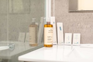 Een bad/douchecombinatie, een haardroger, handdoeken, zeep