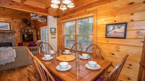 A wooden cabin interior with a dining table set for four, surrounded by wooden chairs. - Spacious Boone log cabin with 4 bedrooms, 3 baths, river access and game room (Boone)