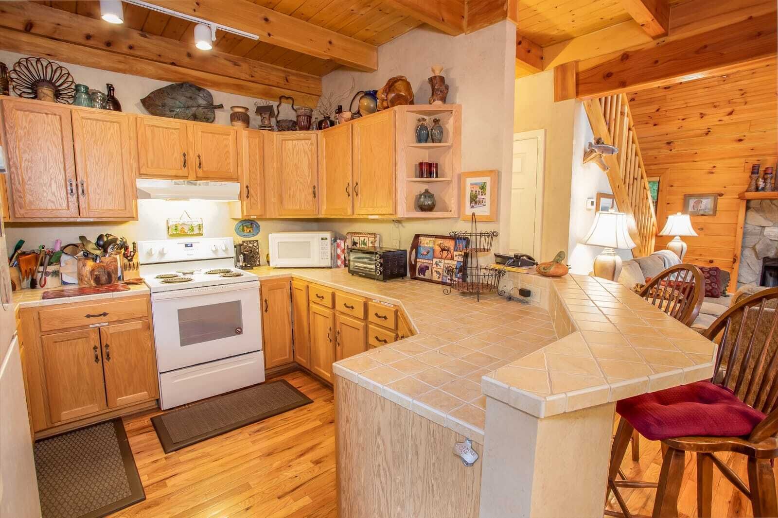 A kitchen with wooden cabinets, a stove, a microwave, and a dining area with a table and chairs.