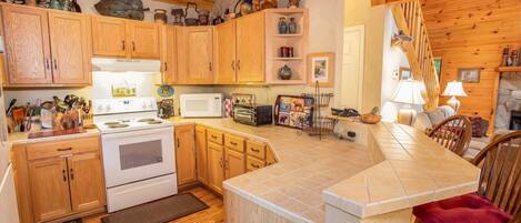 A kitchen with wooden cabinets, a stove, a microwave, and a dining area with a table and chairs.